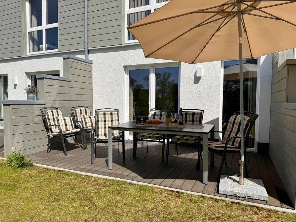 eine Terrasse mit Tisch und Stühlen und einem Sonnenschirm in der Unterkunft Haus Nr 18, Ferienhaus Fischerhus in Wangerland