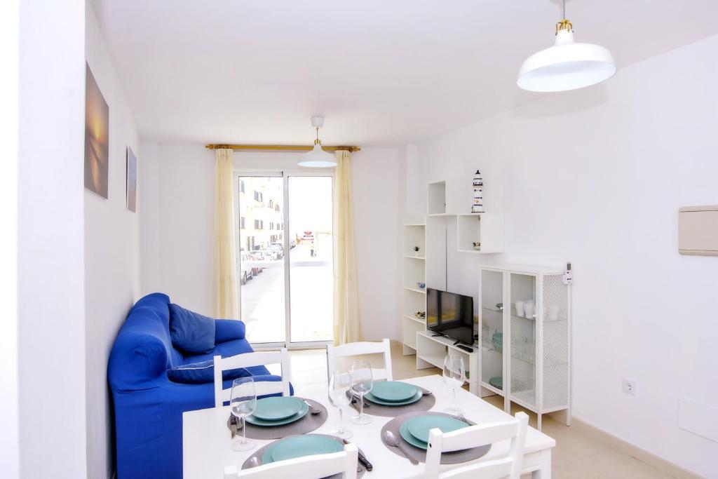 a living room with a blue couch and a table and chairs at La Puntica in Carboneras