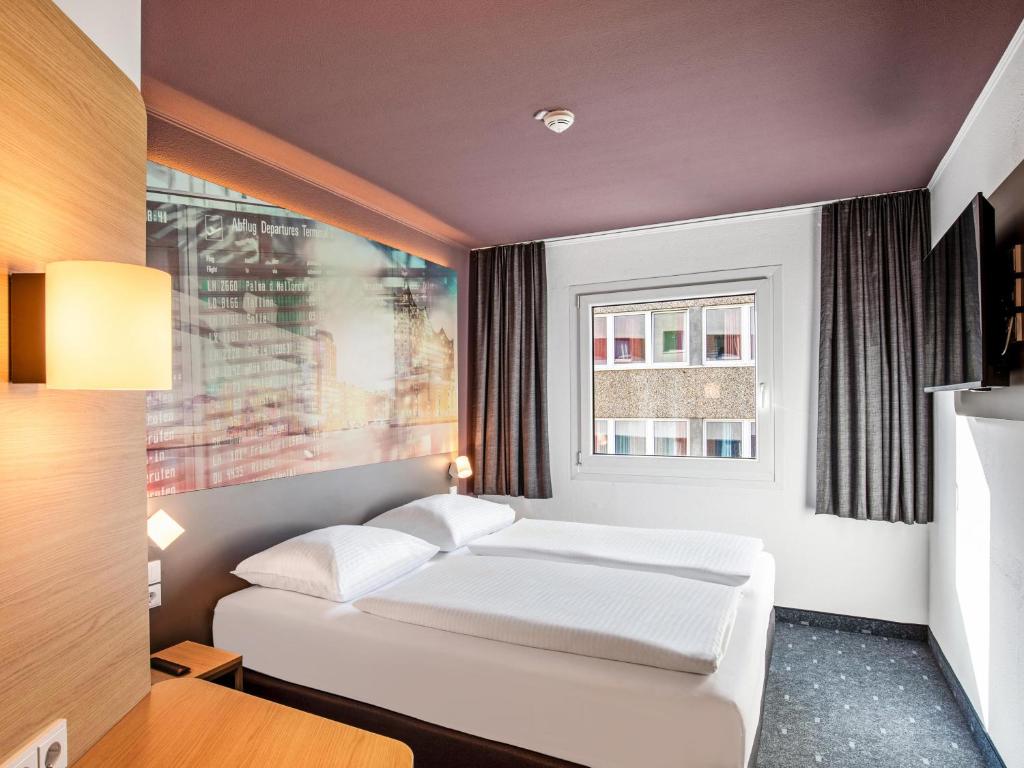 a bedroom with a white bed and a window at B&B Hotel Hamburg-Airport in Hamburg