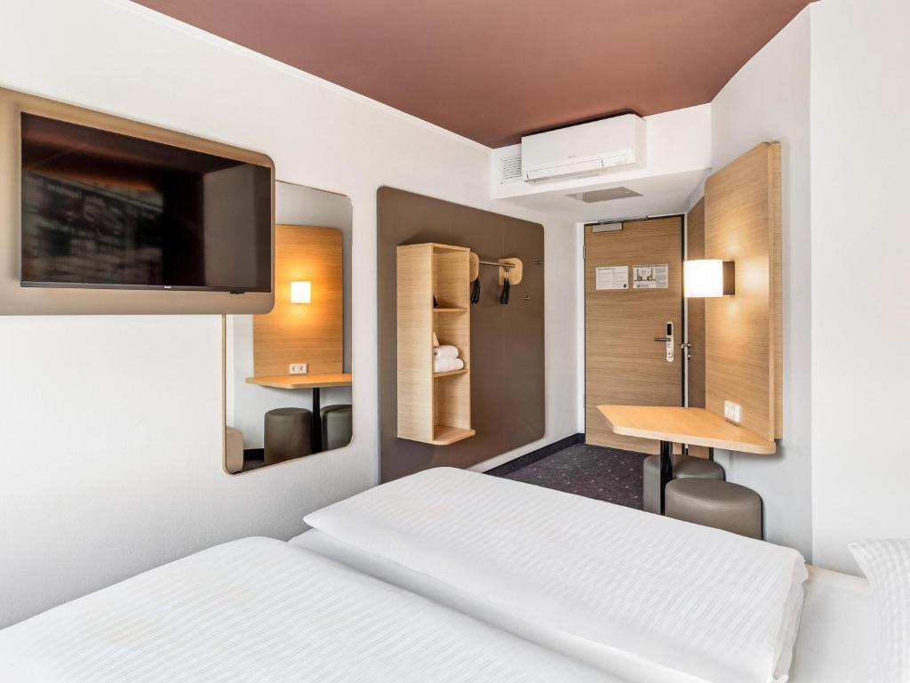 a bedroom with a bed and a desk and a tv at B&B Hotel Hamburg-Airport in Hamburg