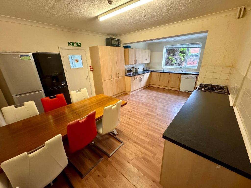 uma cozinha com uma mesa de madeira e cadeiras vermelhas em Clare House - sleeps 14 em Bedford