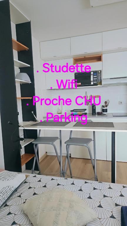 a desk with two stools in a room with pink writing at Le Cocon - Studio proche du CHU in Saint-Denis