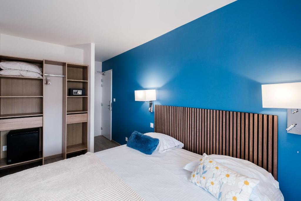 Schlafzimmer mit blauen Wänden und einem Bett in der Unterkunft Anglade Hotel in Le Lavandou