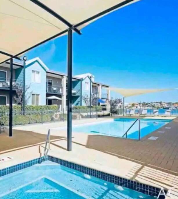 曼哲拉Apartment in Apollo Quays resort with shared Jetty的房屋前带遮阳伞的游泳池