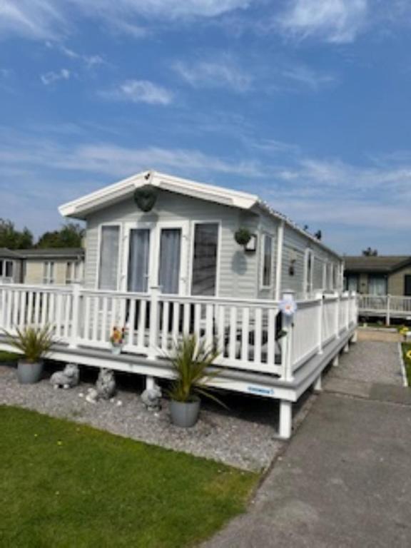 a white house with a porch and potted plants at Presthaven sands P&Ts home from home in Talacre