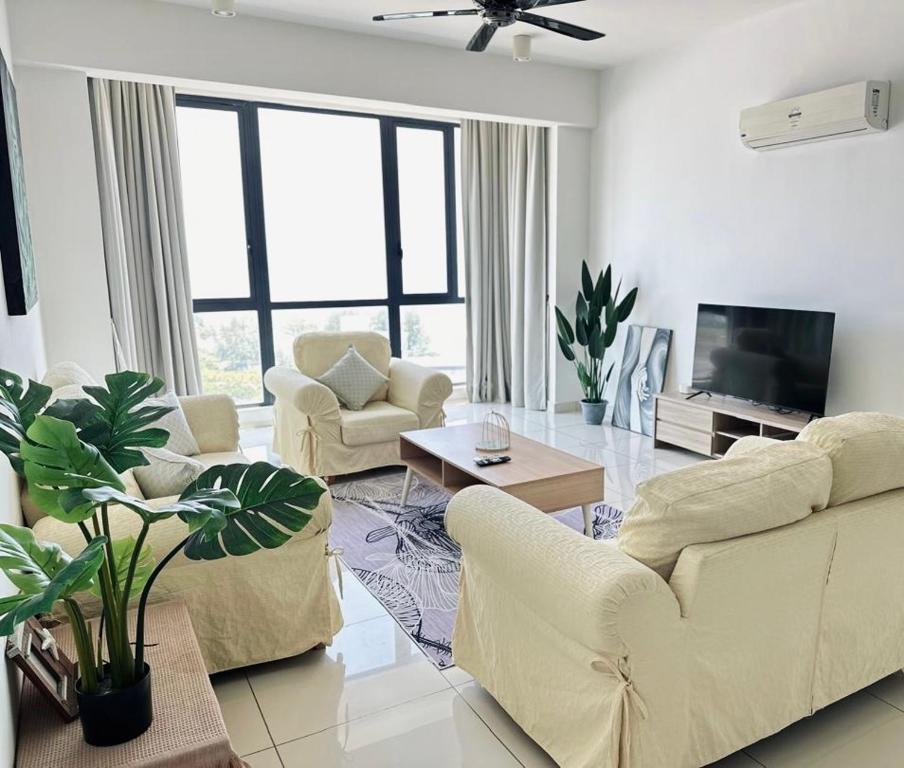 a living room with a couch and chairs and a tv at Jazz Suites Seaview with Bathtub - 1603 in Tanjong Tokong