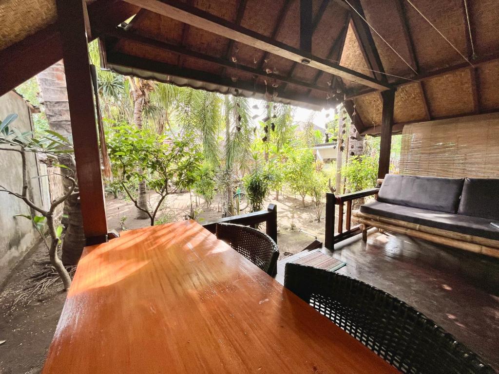 a wooden table and chairs on a porch with a couch at Little Bear Bungalows in Gili Air