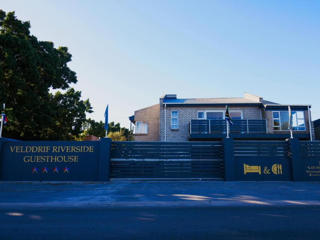 a gate with a sign in front of a building at Velddrif Riverside Guesthouse in Velddrif