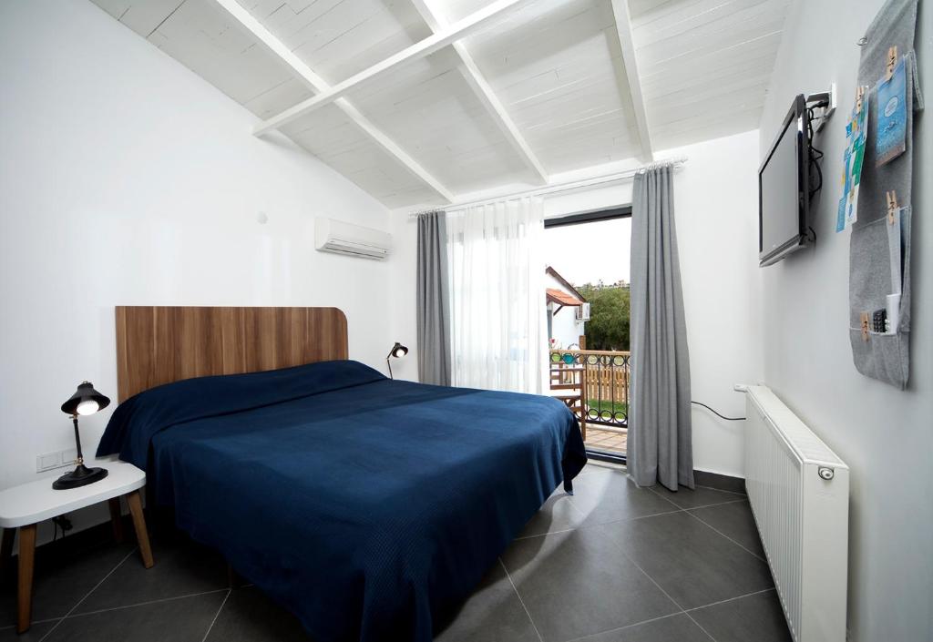 ein Schlafzimmer mit einem blauen Bett und einem Fenster in der Unterkunft Maya Bistro Hotel & Beach in Siğacık