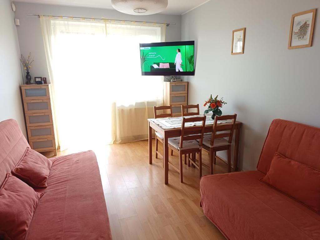 a living room with a couch and a table and a tv at Studio Krynica in Krynica Morska