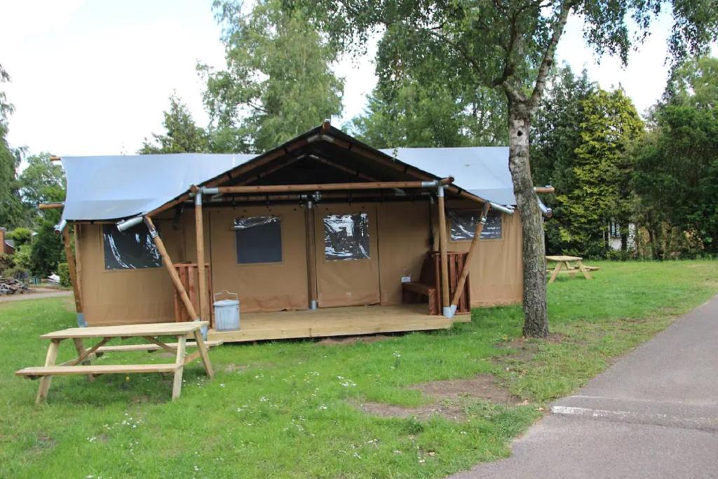 a tent in a field with a table and a tree at Verblijf in de Veluwe met Privé sanitair LL54 in Putten