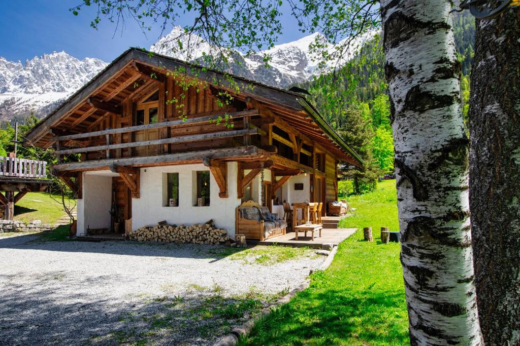 une cabane en rondins avec des montagnes en arrière-plan dans l'établissement Chalet Taconnaz - Warm & Cosy 3BR Chalet with Fireplace in Nature - By Cozee Rentals, aux Houches