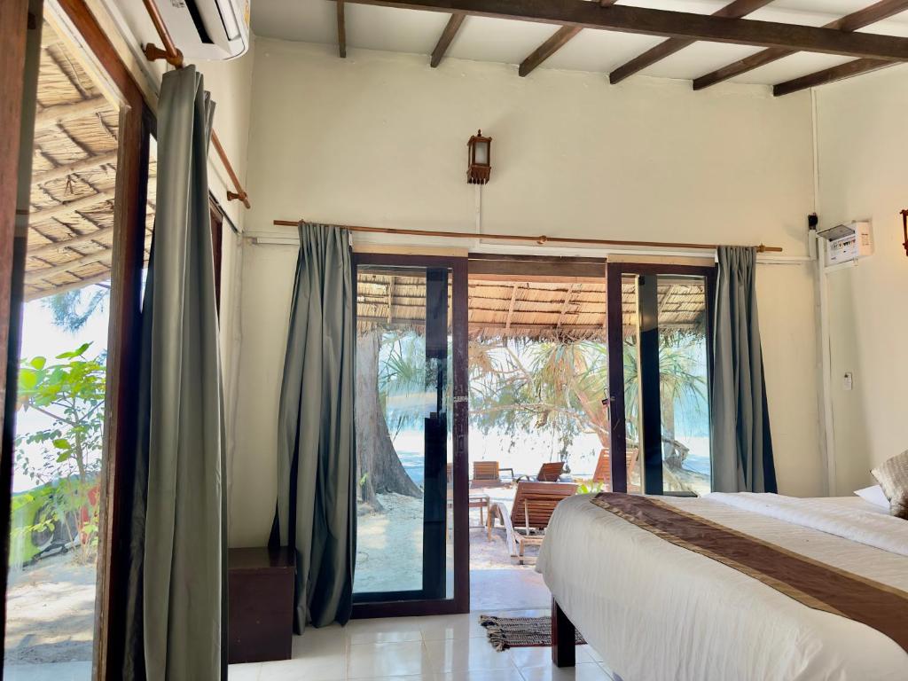 een slaapkamer met een bed en glazen schuifdeuren bij La Ong Lay in Ko Phayam