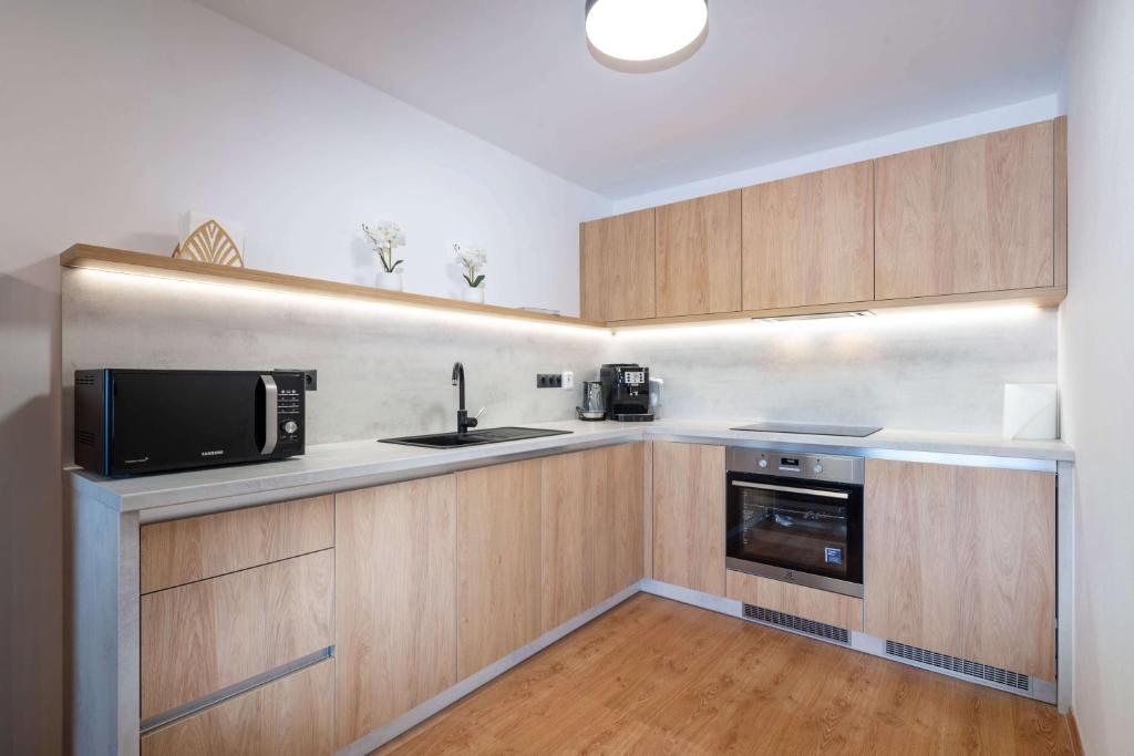 a kitchen with wooden cabinets and a microwave and a sink at Apartmanica Residence 511 in Donovaly