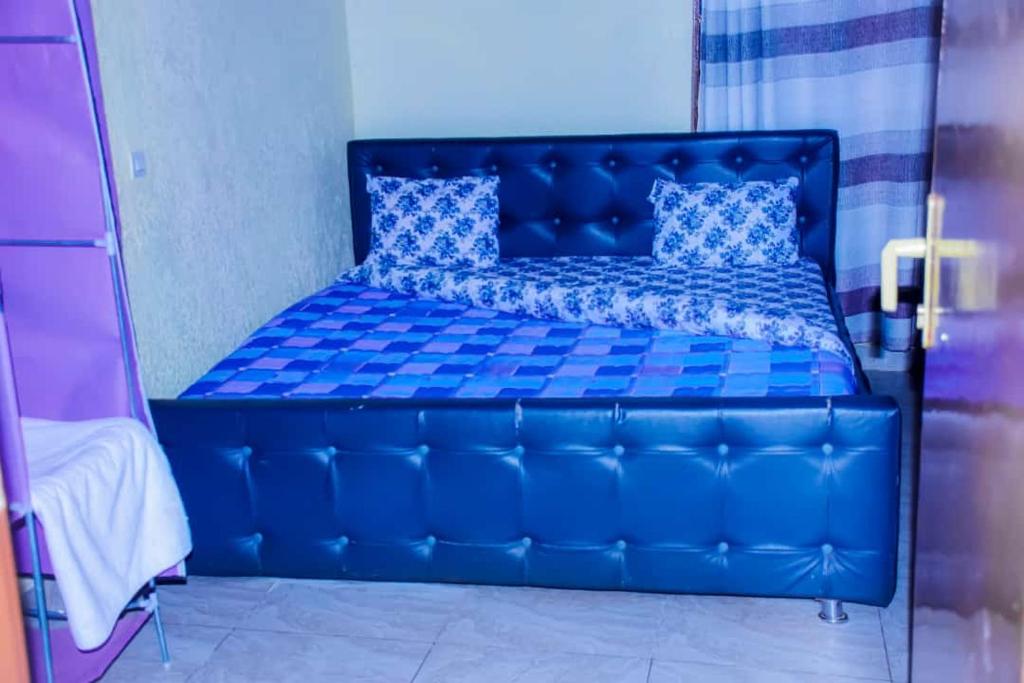 Una cama azul con almohadas azules en una habitación en AIM Kanombe INN MOTEL en Kigali