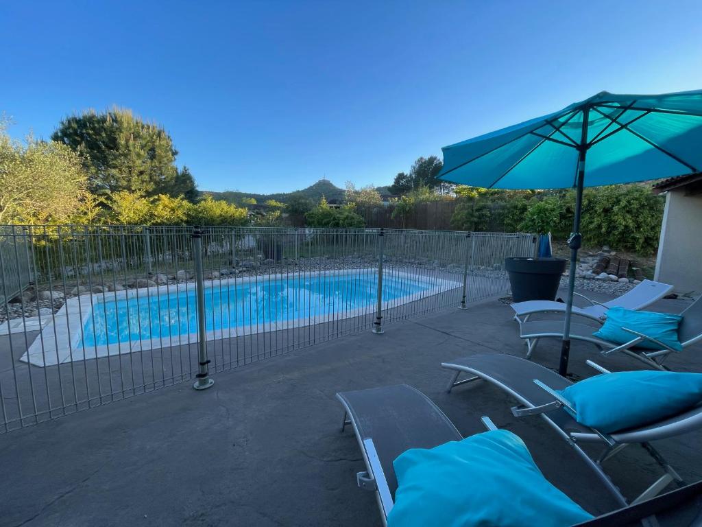 a swimming pool with chairs and an umbrella at Villa MIMOSA in Sampzon