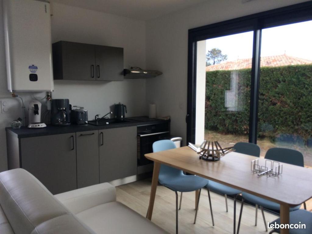 une cuisine et une salle à manger avec une table et des chaises dans l'établissement Joli studio de 25m2 avec terrasse, idéal pour un couple, à Gujan-Mestras