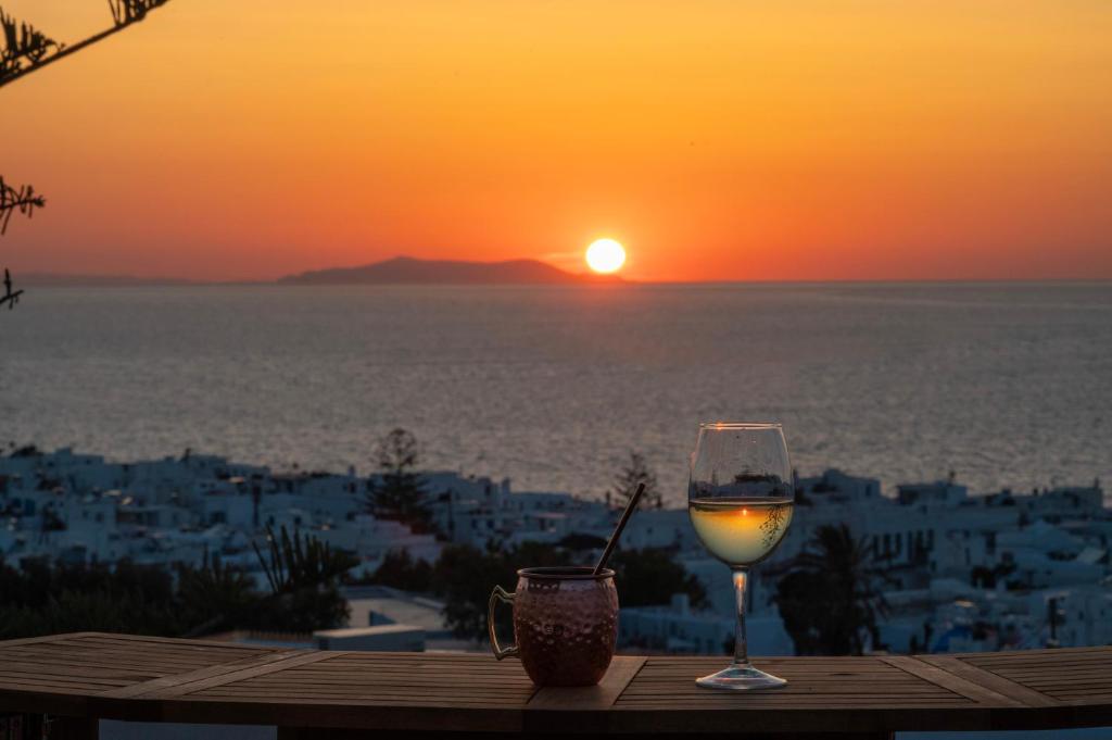 un bicchiere di vino seduto su un tavolo con il tramonto di Boutique di Vito a Mykonos Città