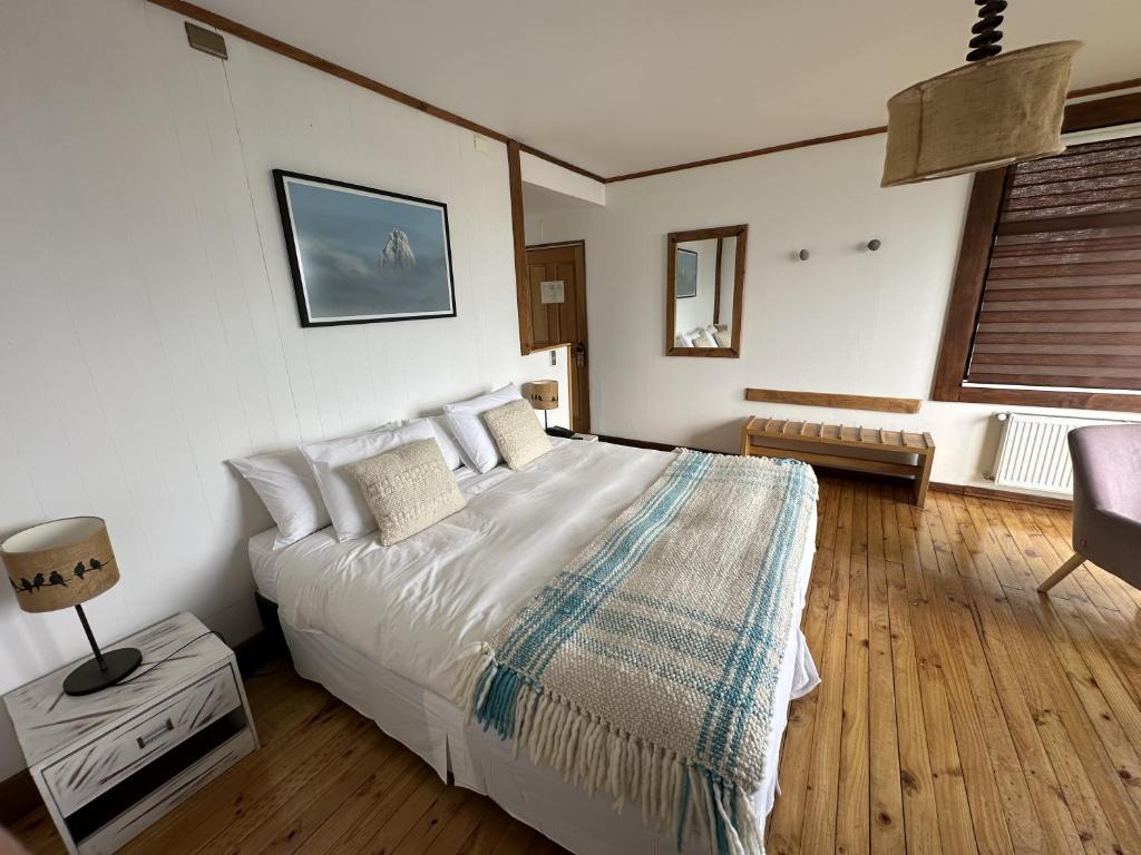 a bedroom with a bed and a chair and a window at Weskar Lodge Hotel in Puerto Natales