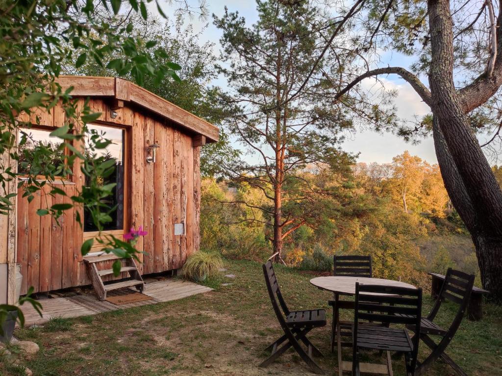 a table and chairs in front of a cabin at La cabane en bois in Villemur-sur-Tarn