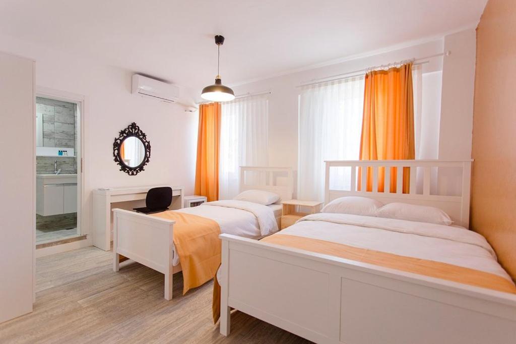 a bedroom with two beds and a desk and a mirror at Ada Kalimera Bozcaada in Bozcaada