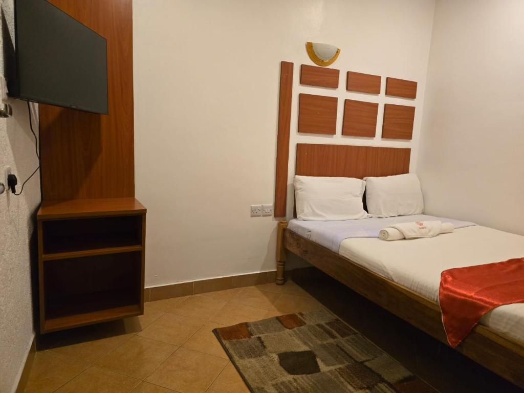 małą sypialnię z łóżkiem i telewizorem w obiekcie Sanrod Hotel Maua w mieście Maua