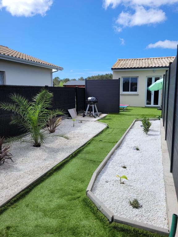 un jardin avec de l'herbe et du gravier et une maison dans l'établissement Petite maison neuve proche du lac, à Parentis-en-Born