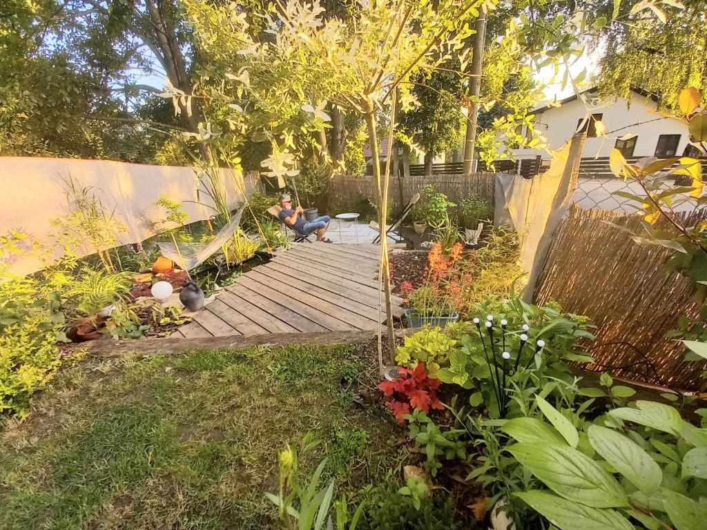 a woman sitting on a wooden walkway in a garden at Lazy Bee in Keszthely