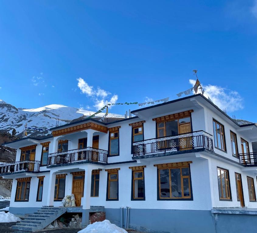 a white house with a balcony and mountains in the background at The Shangbar in Jispa