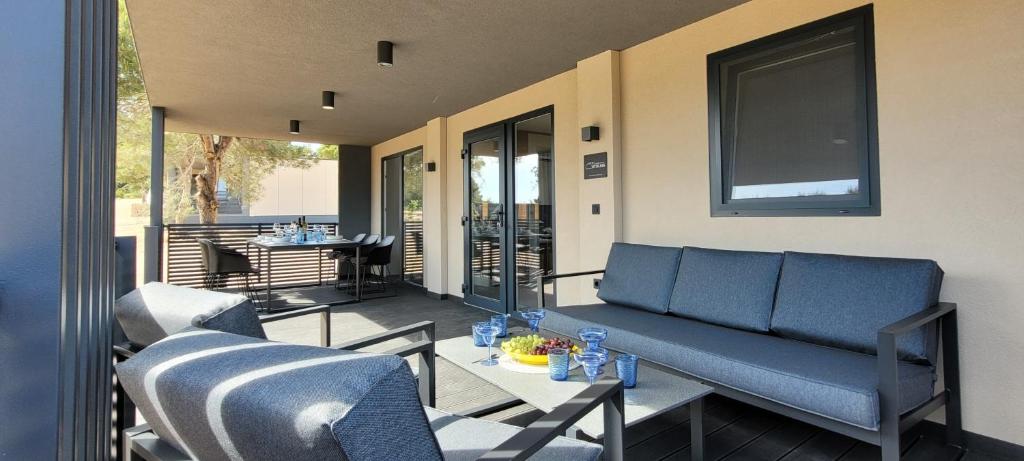 eine Terrasse mit Sofa, Stühlen und einem Tisch in der Unterkunft Adriaticoast Holiday Apartments- Blue Horizon in Drage