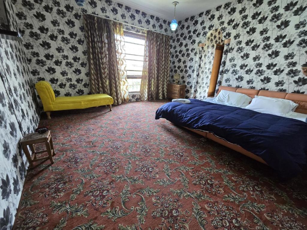 um quarto com uma cama e uma cadeira amarela em The Citadel em Srinagar