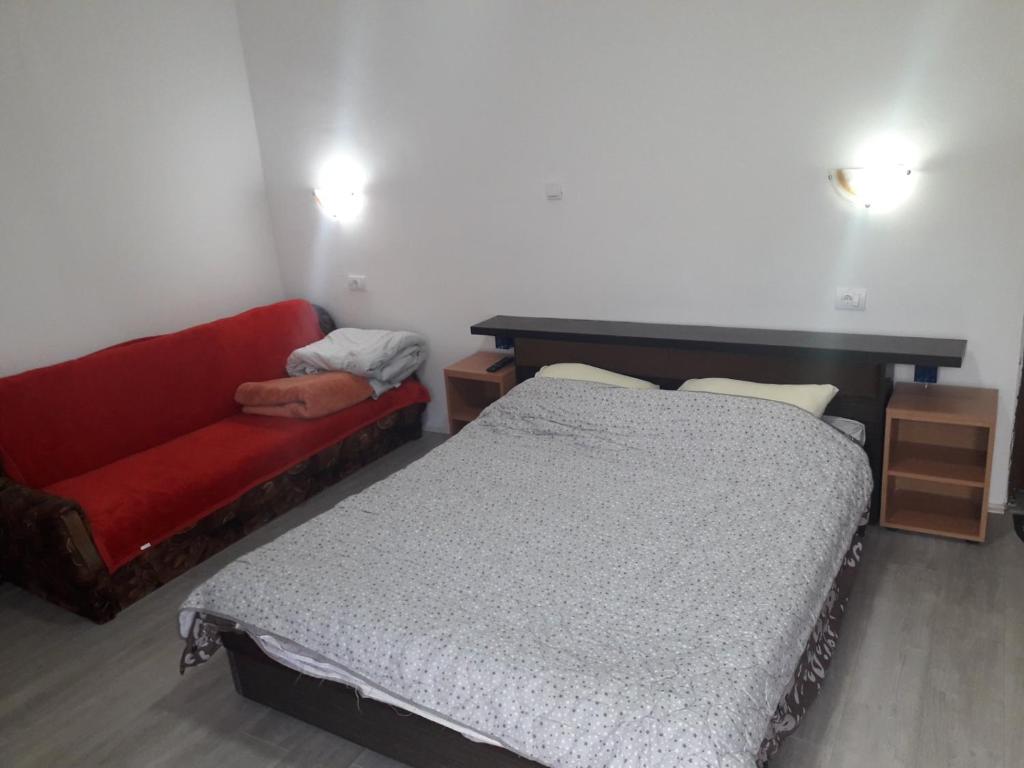 a bedroom with a bed and a red couch at Apartmani Zivkovic Ribarska banja in Ribarska Banja