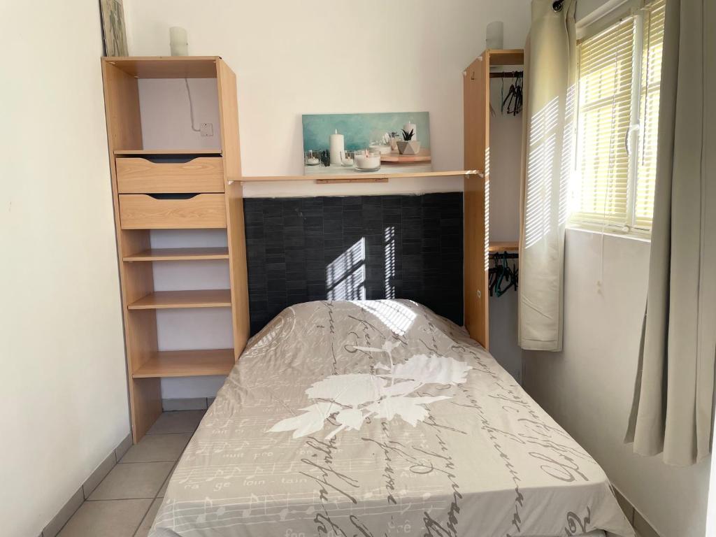 a small bedroom with a bed and a shelf at Maisonnette au calme in Montauroux