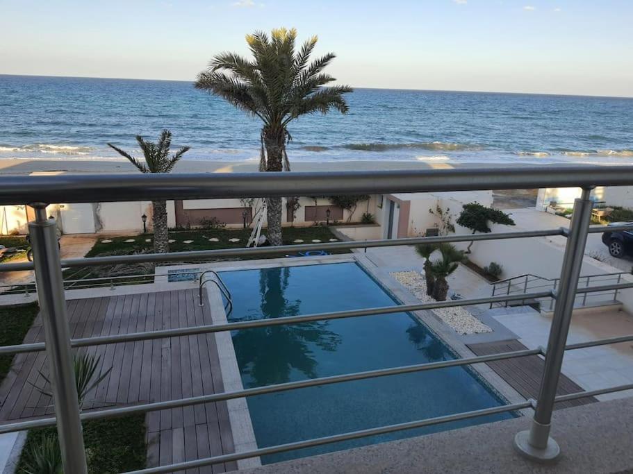 a balcony with a swimming pool and the ocean at Gorgeous Villa in Salakta Mahdia in Salakta