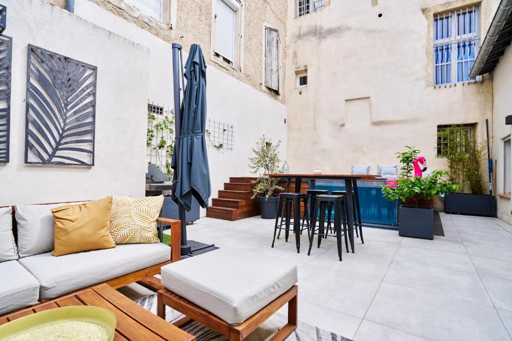eine Außenterrasse mit einem Sofa und einem Tisch in der Unterkunft Maison de ville moderne climatisée avec piscine in Morières-lès-Avignon