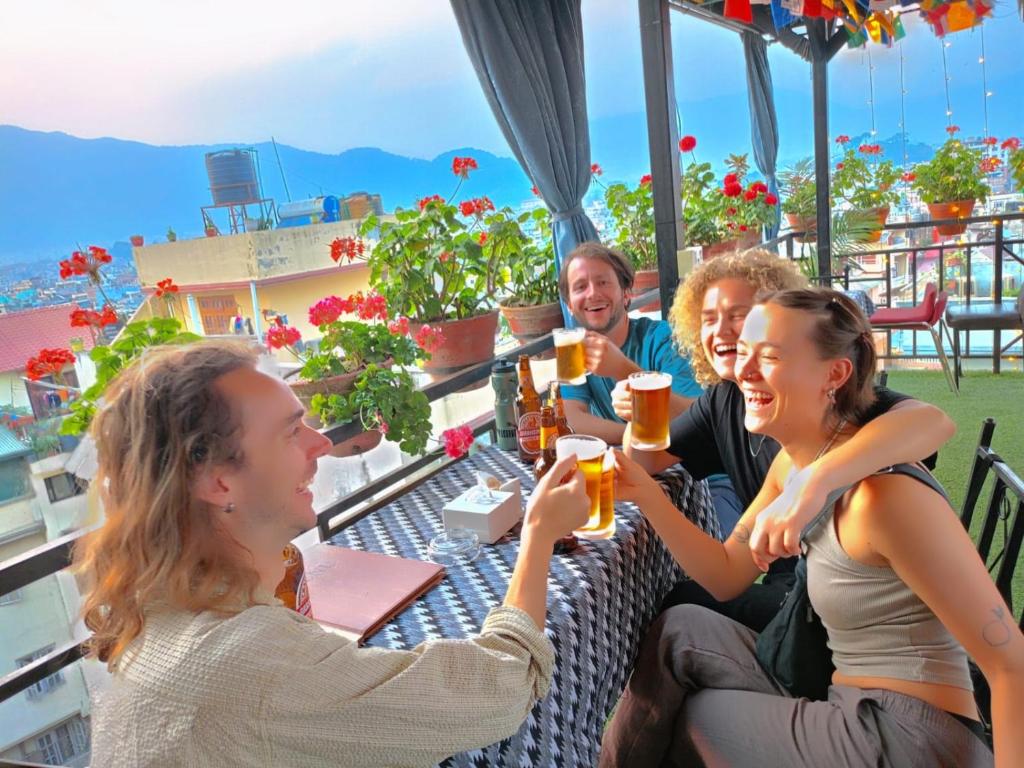 een groep mensen die aan een tafel bier drinken bij Yog Hostel in Kathmandu