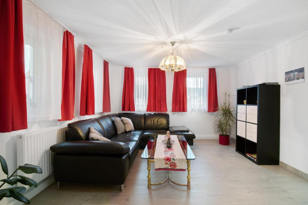 a living room with a leather couch and red curtains at Ferienhaus Doris in Bad Urach