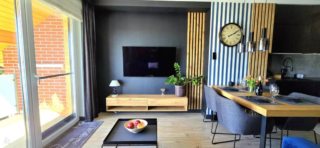 a living room with a table and a clock on a wall at Apartament Bursztynowy Jantar by TriApart in Jantar