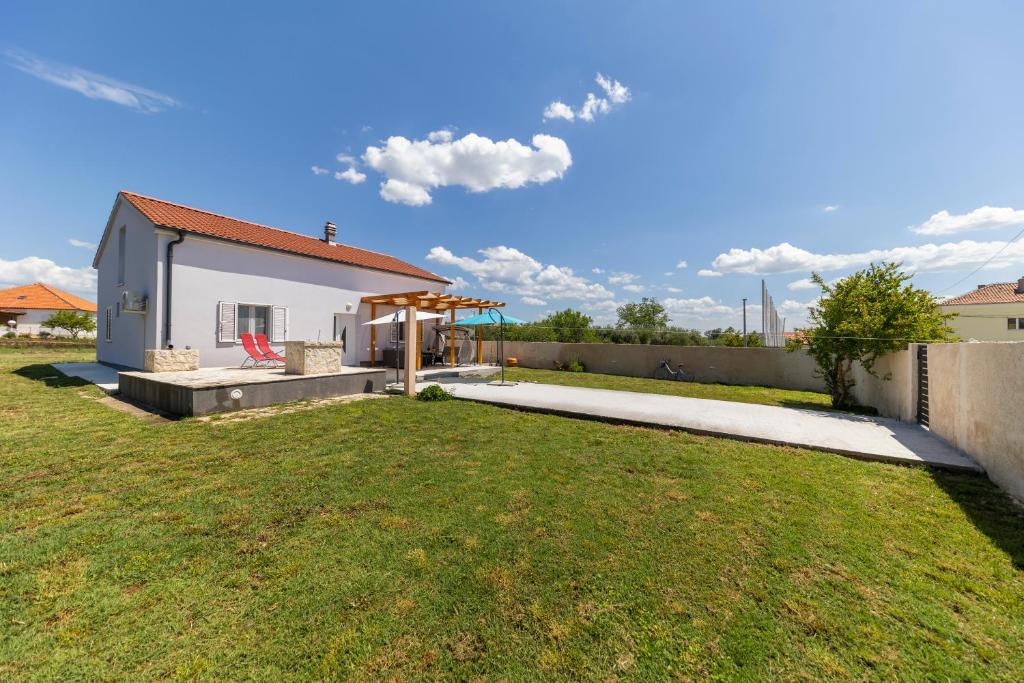 uma pequena casa branca com um jardim de relva em Holiday House Beram em Zadar