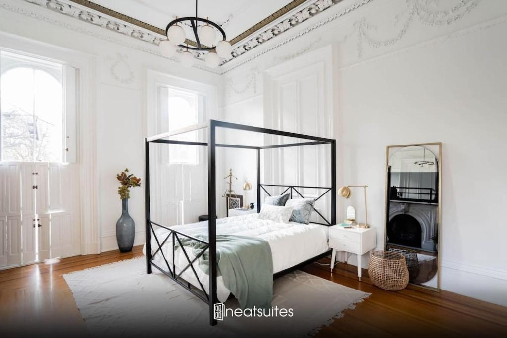 ein weißes Schlafzimmer mit einem großen Bett und einem Spiegel in der Unterkunft Decadent Luxury - Covington Condo in Covington