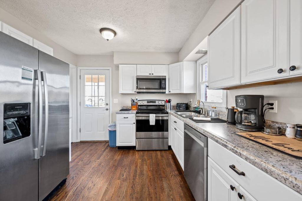 a kitchen with white cabinets and a stainless steel refrigerator at Cozy Brick Cottage near Ark in Williamstown