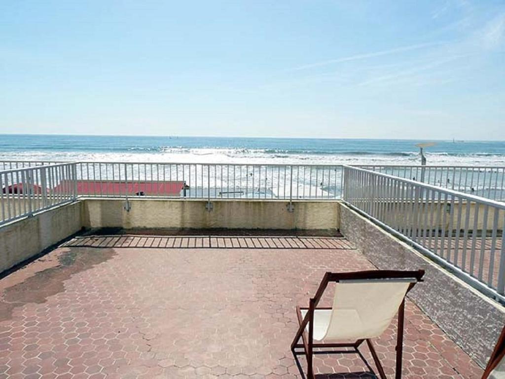 une chaise assise sur un balcon donnant sur la plage dans l'établissement Studio les Chardonnettes, à Saint-Gilles-Croix-de-Vie