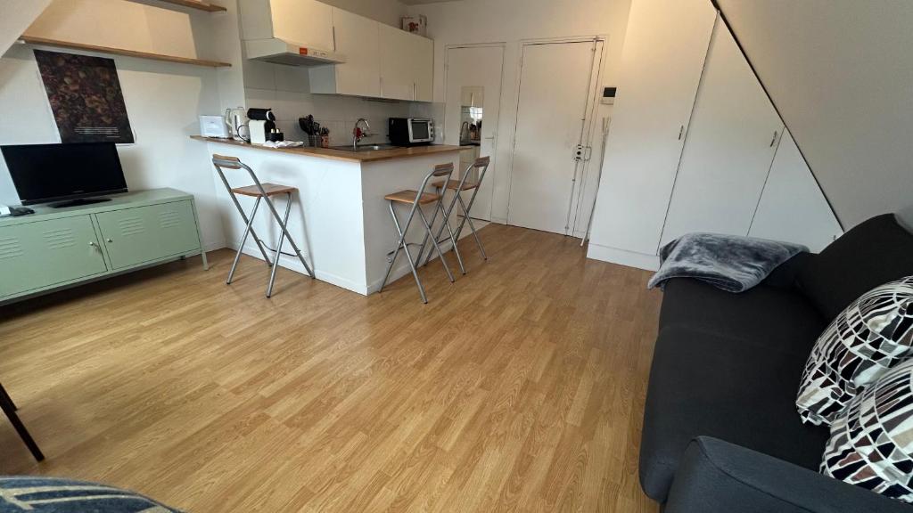 un salon avec un canapé et une cuisine dans l'établissement Studio Porte Maillot Immeuble Haussmannien, à Neuilly-sur-Seine