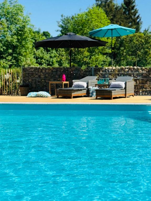 two chairs and umbrellas next to a swimming pool at Sievershof Sieversloft in Wietzendorf
