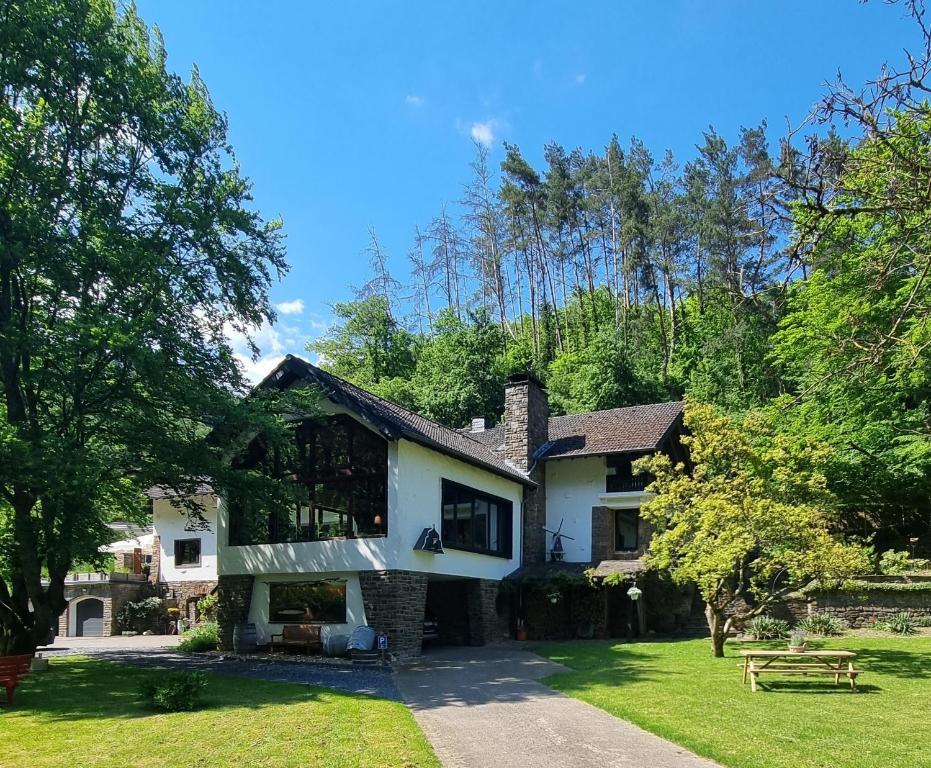 een wit huis met bomen en een grasveld bij B&B Am Sahrbach in Altenahr