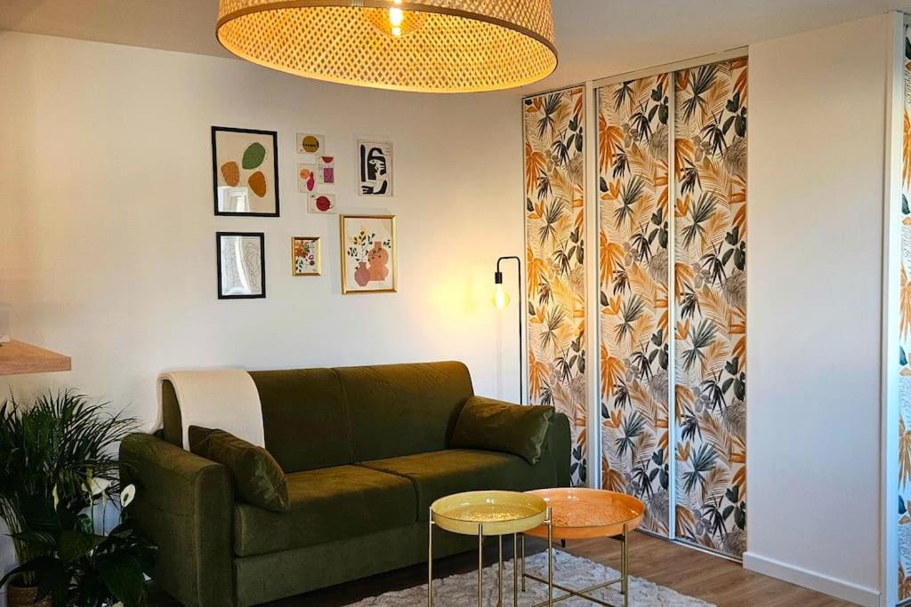 un salon avec un canapé vert et une table dans l'établissement Appartement proximité directe Rouen, à Sotteville-lès-Rouen