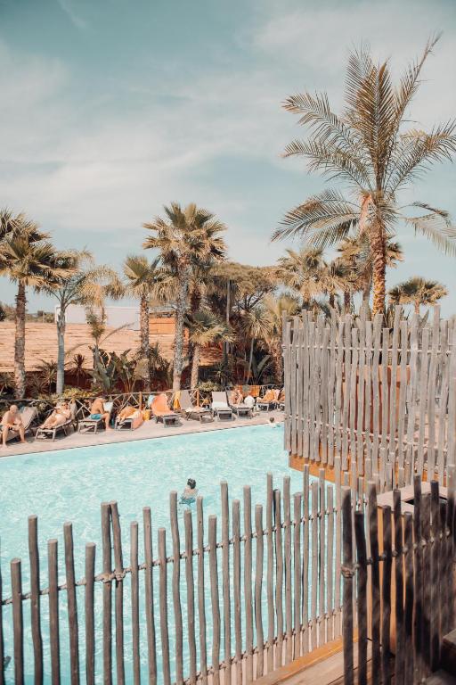 a fence next to a swimming pool with palm trees at Toison D'or in Saint-Tropez