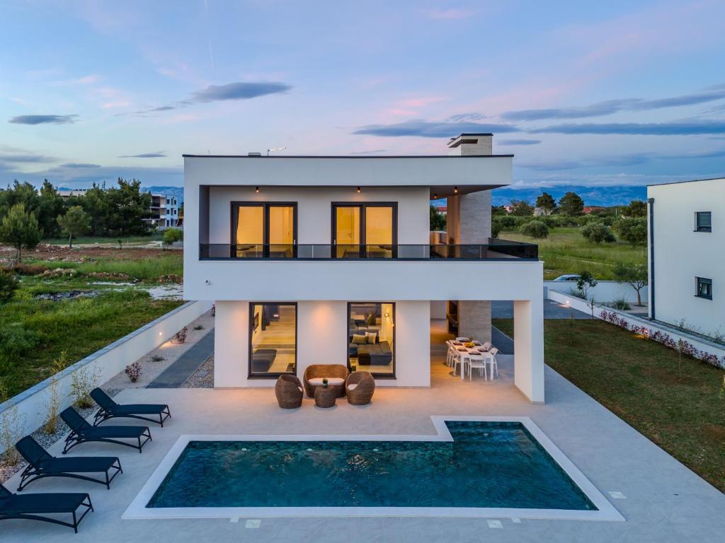 een huis met een zwembad ervoor bij Villa Karlo ZadarVillas in Glavan