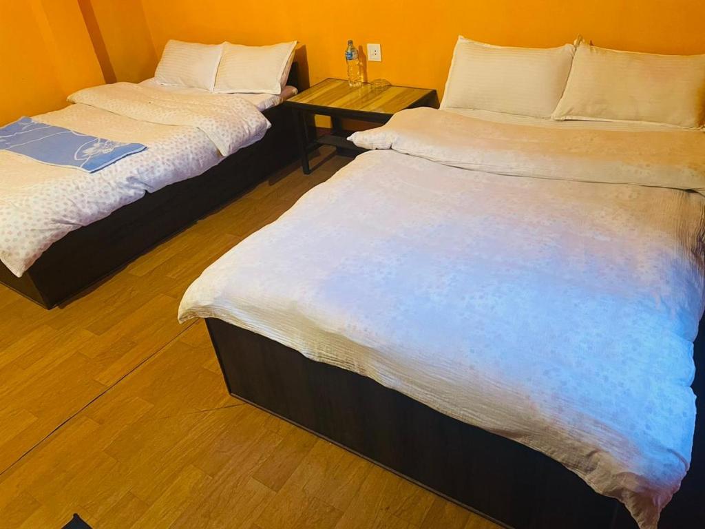 two twin beds in a room with a table at Busy Bee Guest House in Sauraha
