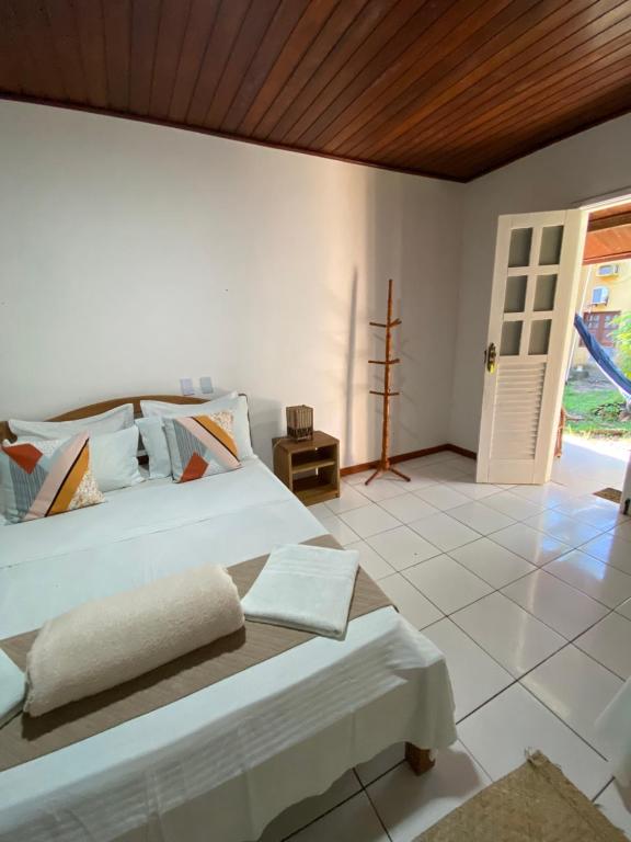 a bedroom with a white bed with a wooden ceiling at Pousada Coco Dendê in Ilha de Boipeba
